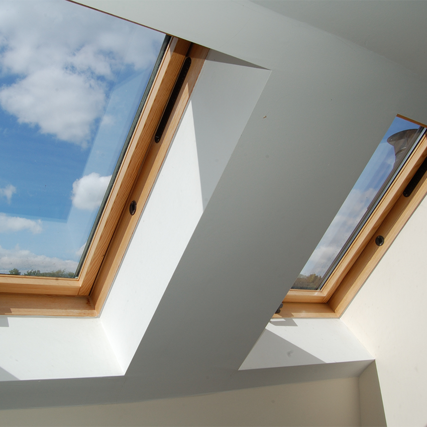 Upward view of two wooden sunlight windows with blue sky and clouds outside.